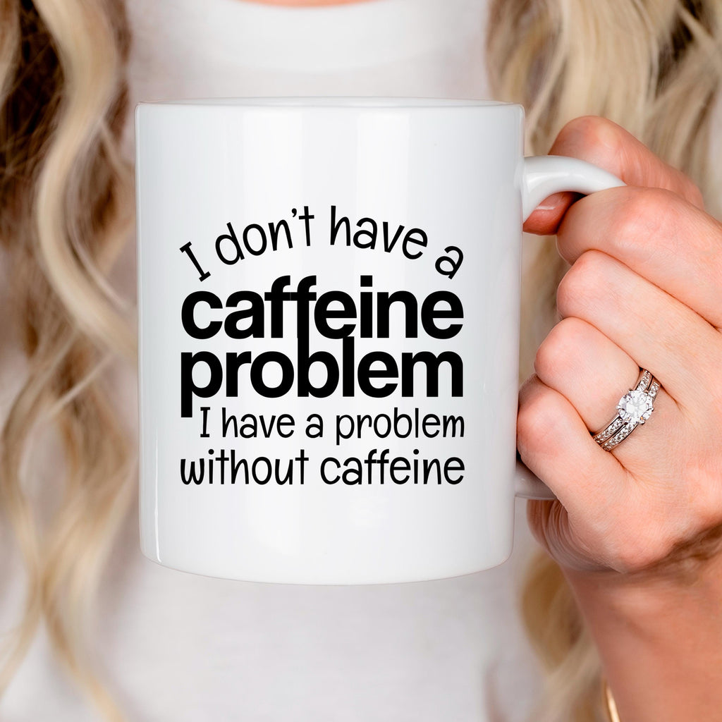 White ceramic mug held by hand, "I don't have a caffeine problem" quote printed