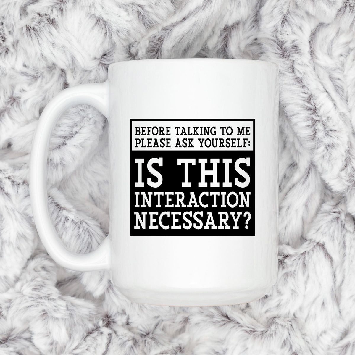 White ceramic coffee mug with black quote: “Is this interaction necessary?”