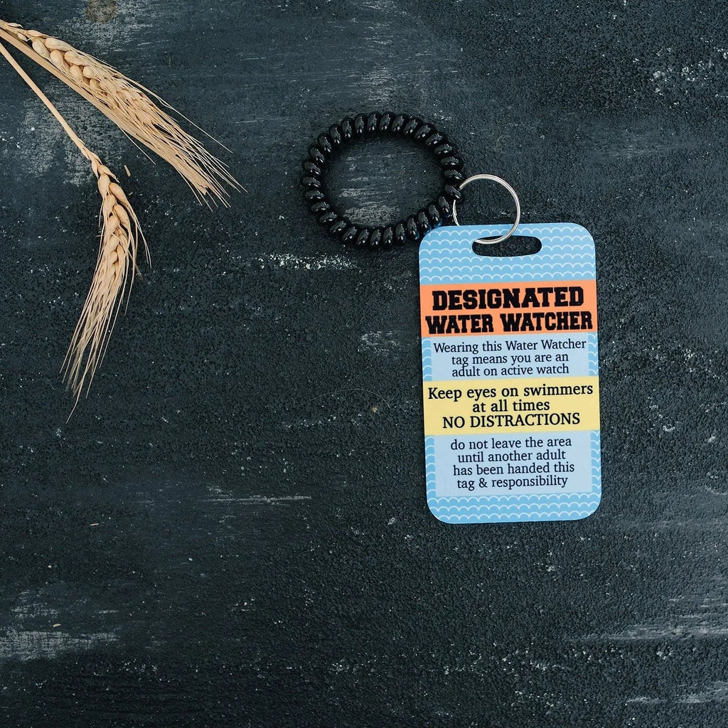 Pool safety badge tag with black beaded lanyard and blue card on dark surface