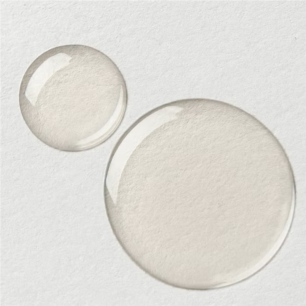 De-stress massage oil swatch, circular pale cream oil spread on white