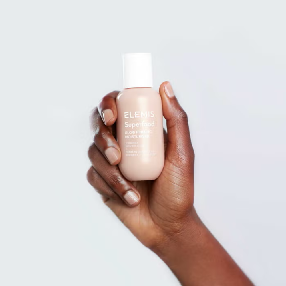 Elemis glow priming moisturiser held in hand, beige bottle