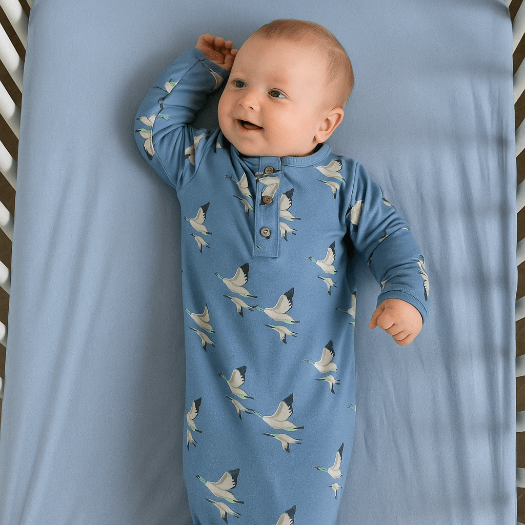 Blue bird-print baby gown with long sleeves, button placket, and knotted bottom