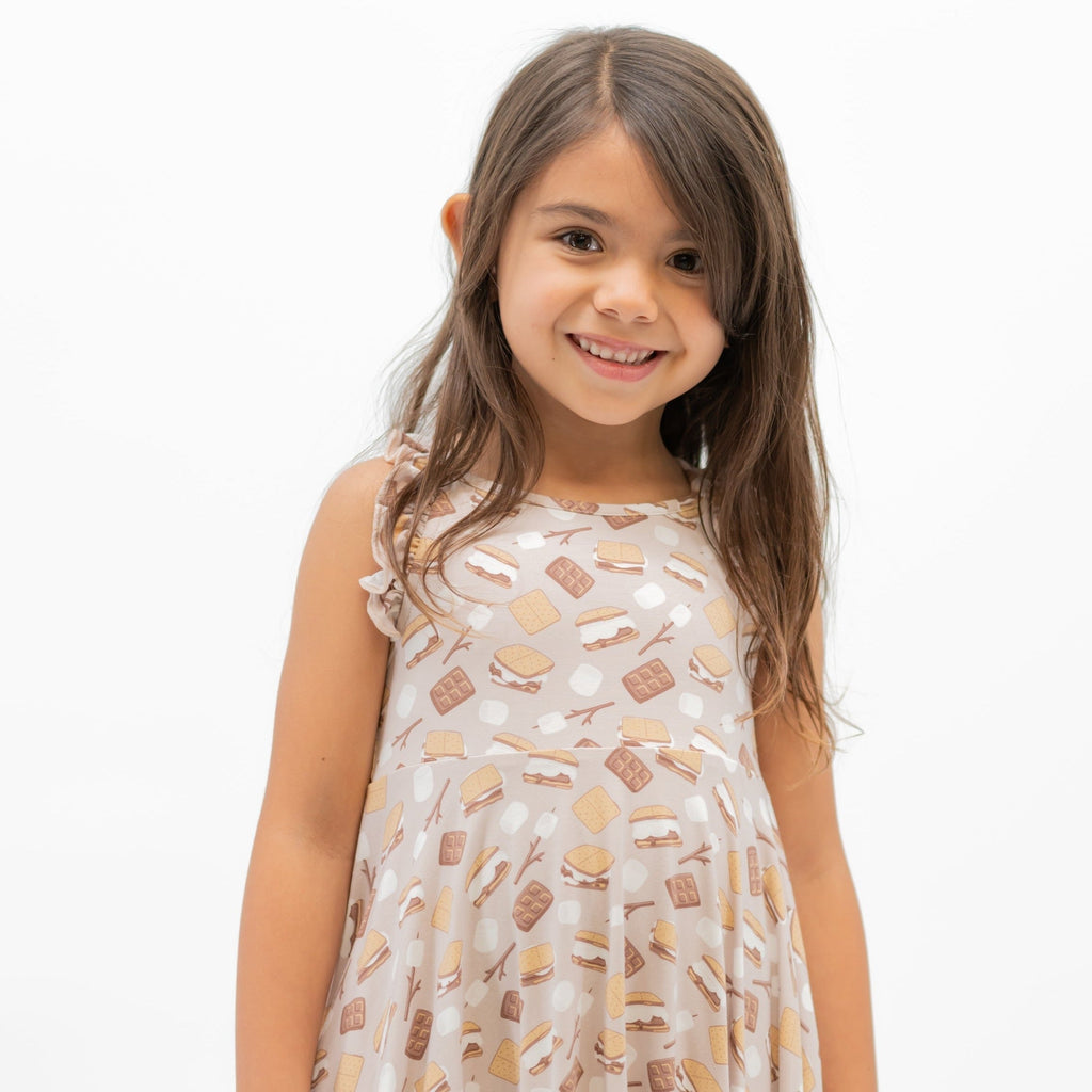 Girls racerback dress on model, light pink with snack print and sleeveless ruffle shoulders