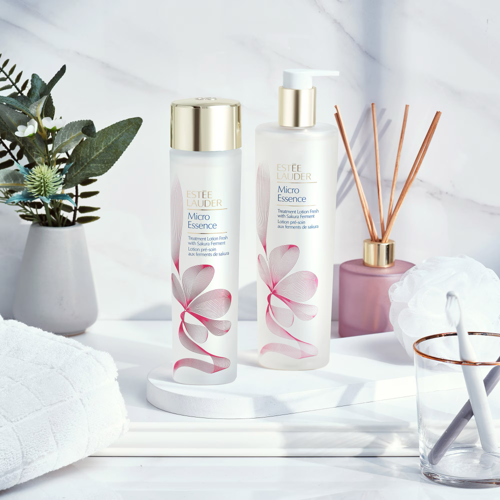 Estee Lauder Micro Essence toner lotion bottles with gold caps and sakura print.