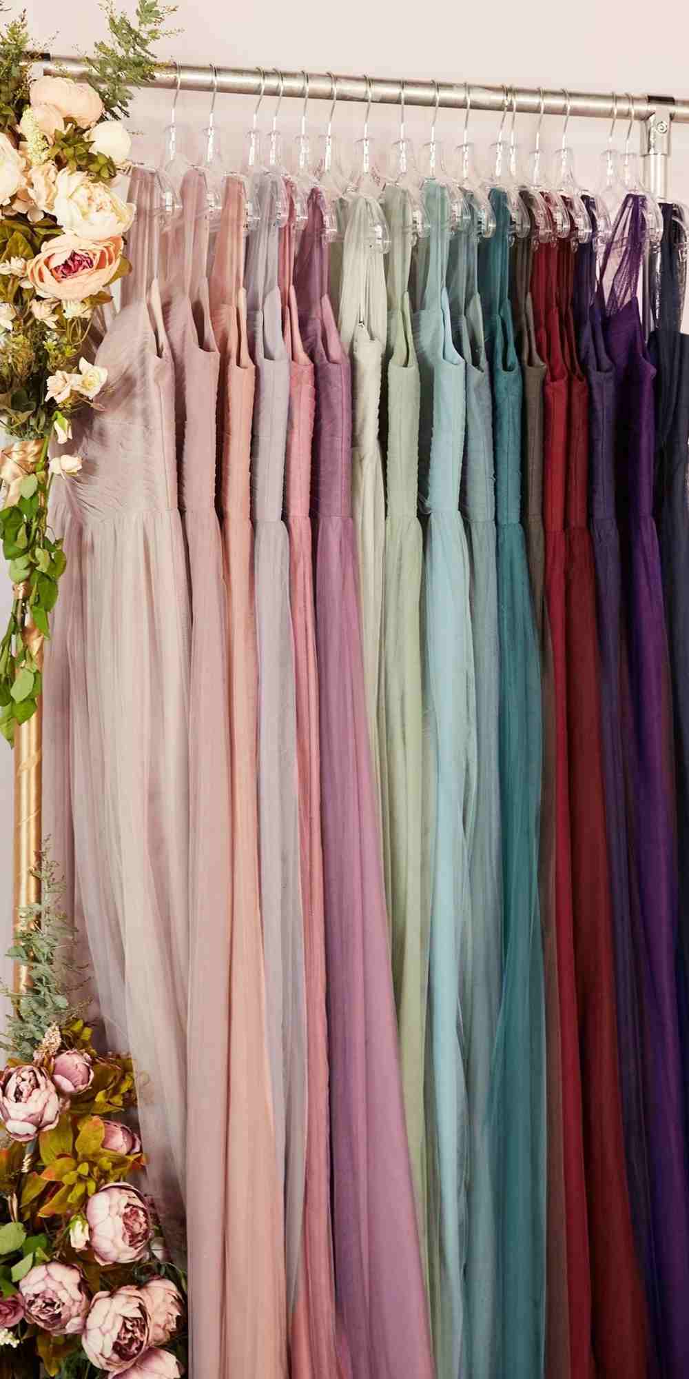 Hanging long sleeveless formal dresses in pastel and dark shades, layered tulle