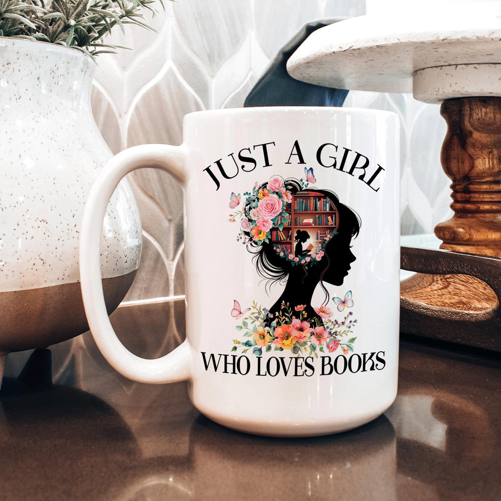 White ceramic coffee mug with floral bookshelf graphic and “WHO LOVES BOOKS” text.