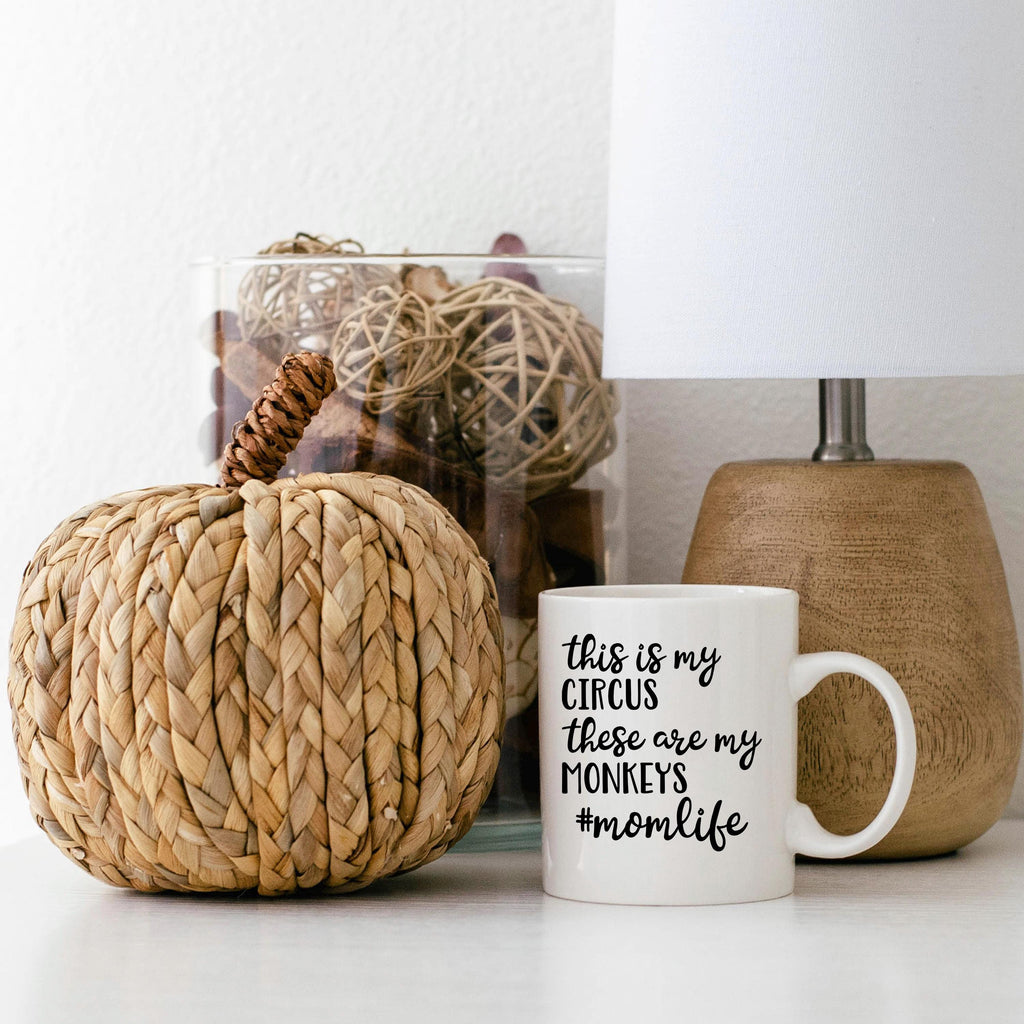 White ceramic coffee mug with "Circus" momlife message beside home decor
