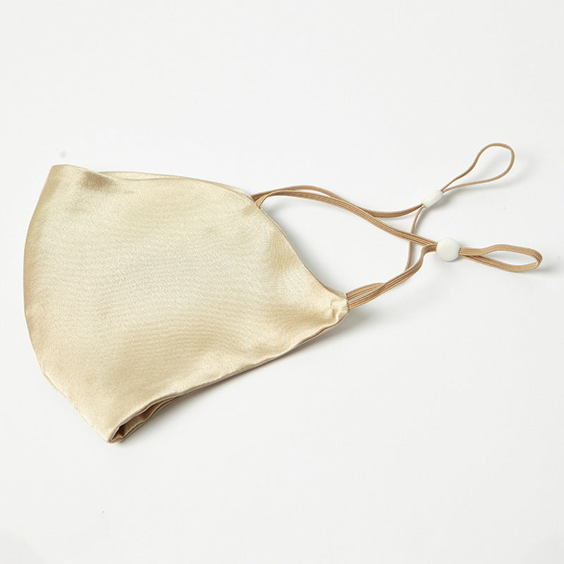 Champagne-gold silk face mask with pleated front and brown drawstring ties