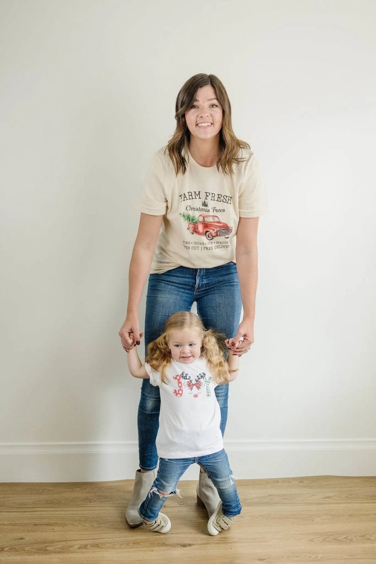 Cream T-shirt with Farm Fresh Christmas Trees red truck graphic, worn with child