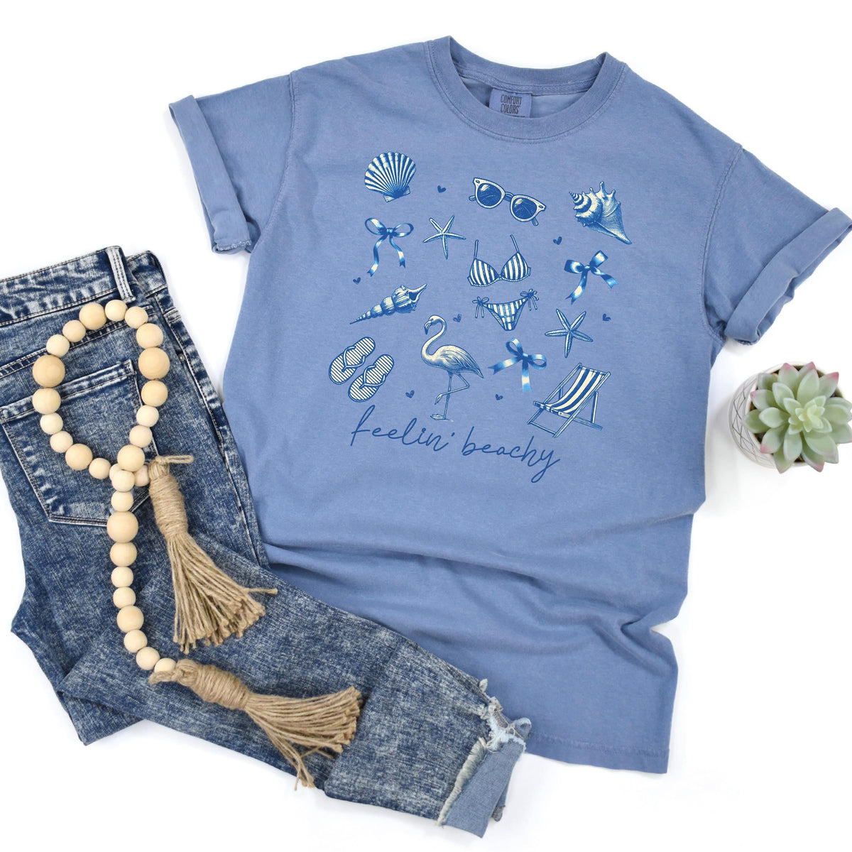 Blue jean unisex beach graphic tee with blue shells and “feelin’ beachy” print