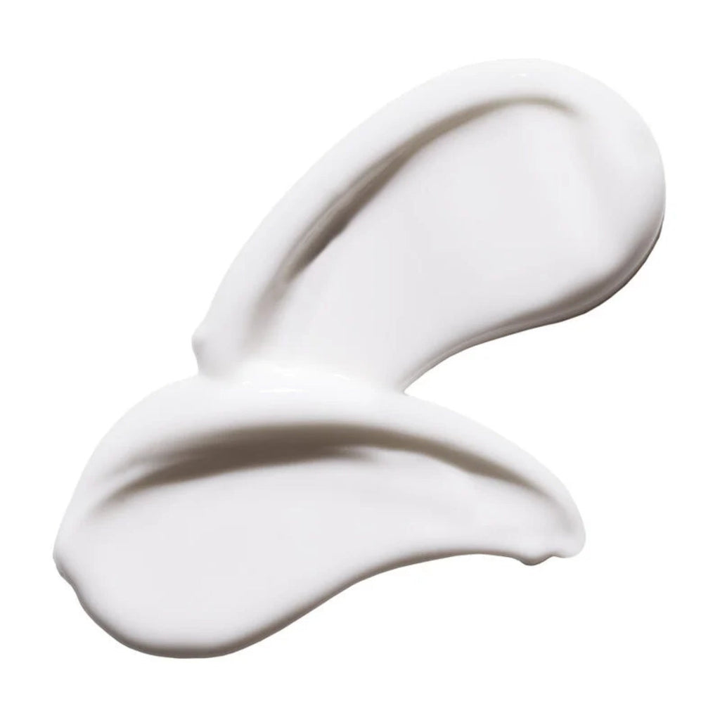 Thick white lotion swatch on spoon, creamy smooth texture.