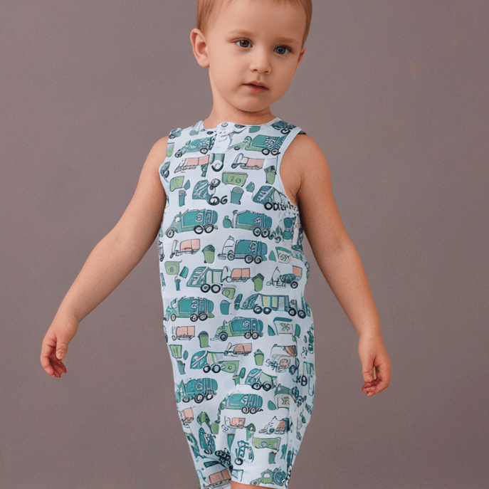 Sleeveless romper with white base and green/blue truck print, worn by baby