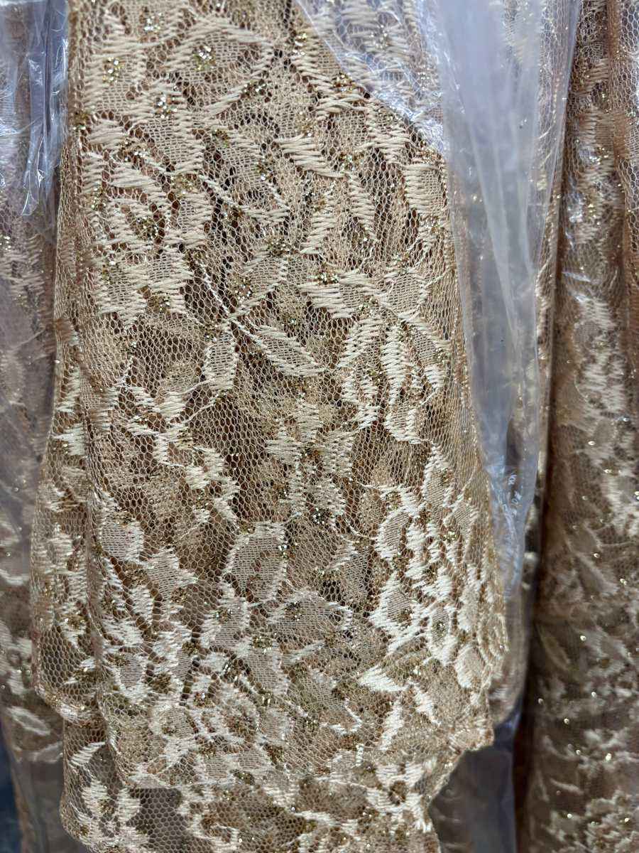 Lace fabric close-up with ornate floral mesh pattern in gold and ivory