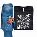 Black unisex crewneck T-shirt with white witch-and-cat graphic and 'Not every witch lives in Salem' text