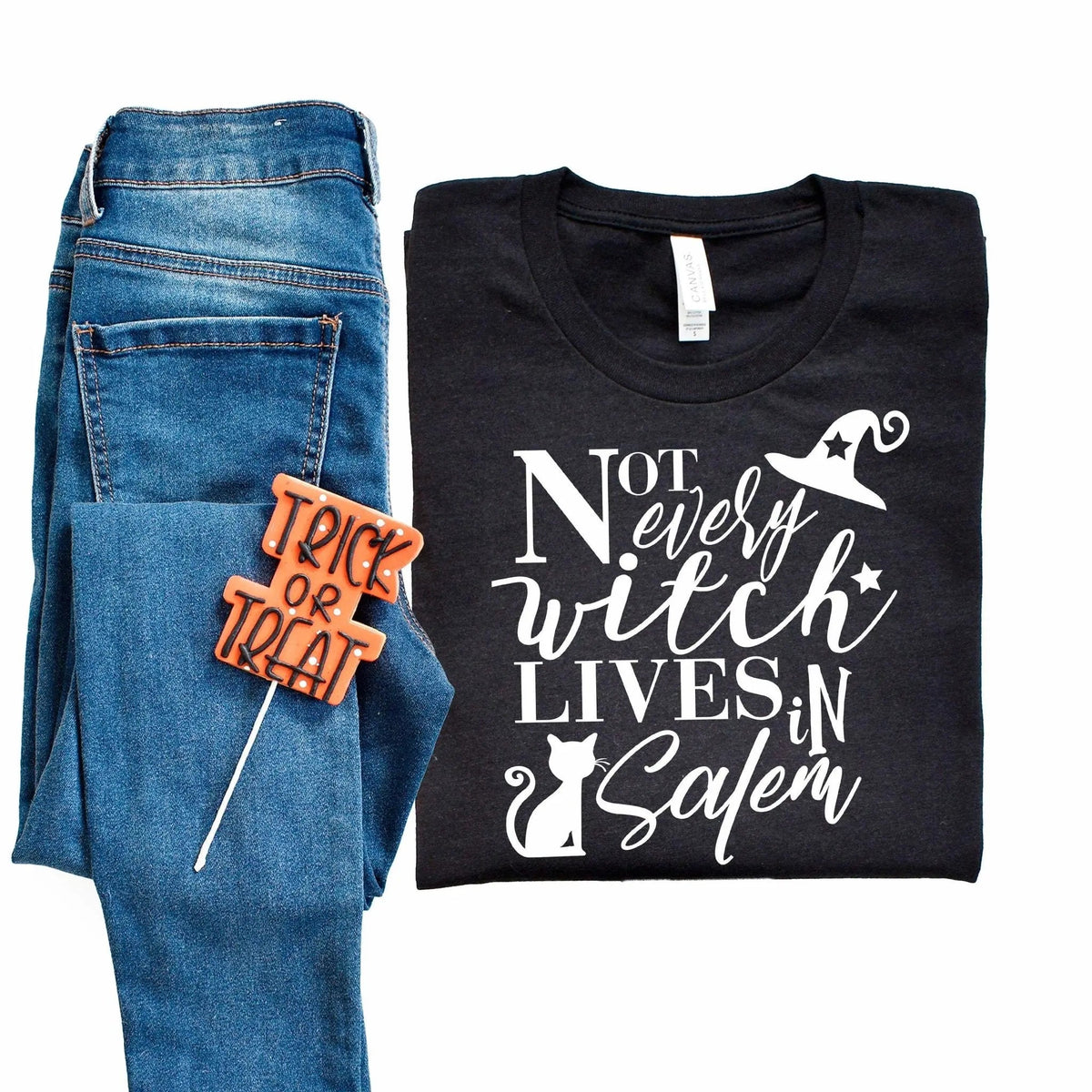 Black unisex crewneck T-shirt with white witch-and-cat graphic and 'Not every witch lives in Salem' text