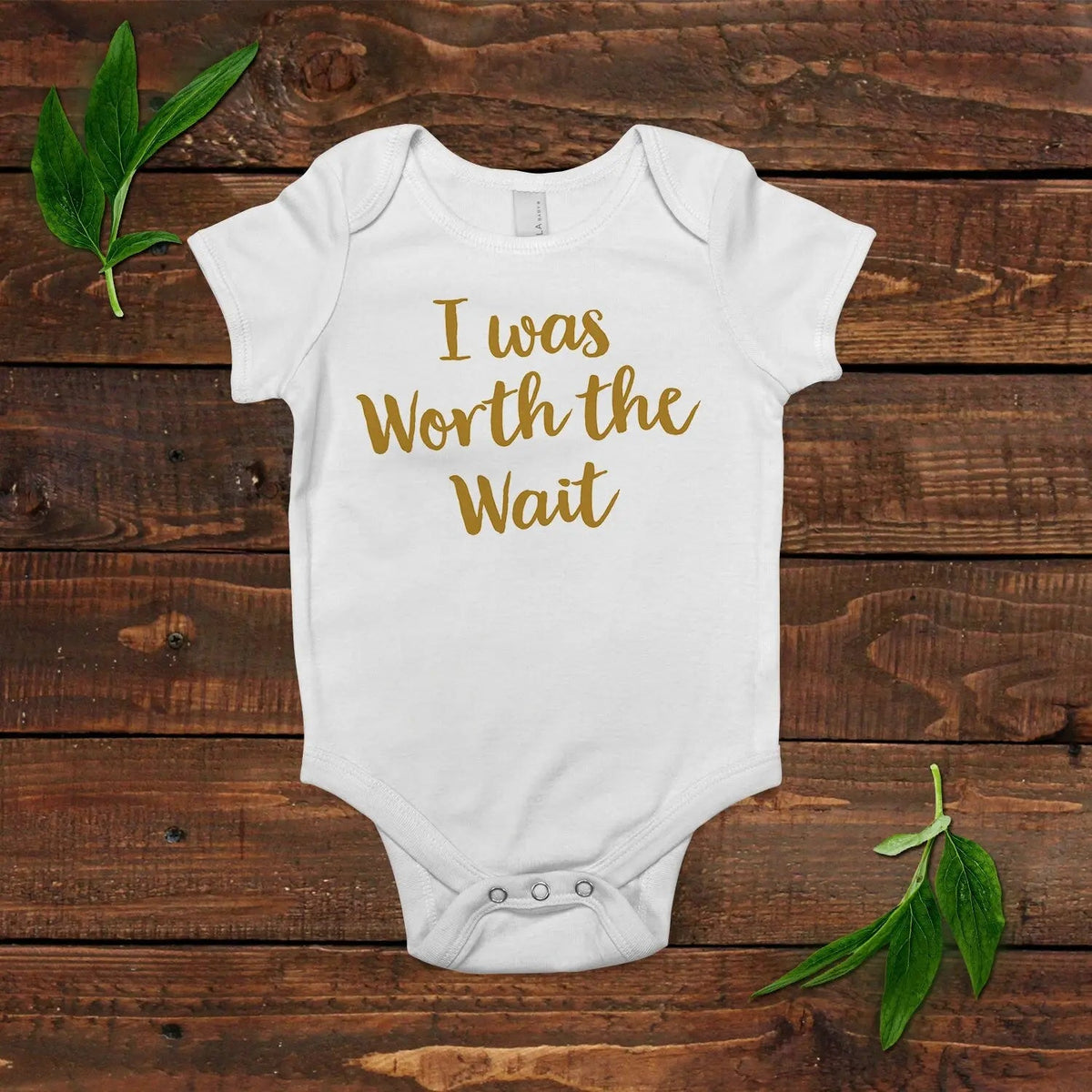 White short-sleeve newborn onesie with gold 'I was Worth the Wait' lettering