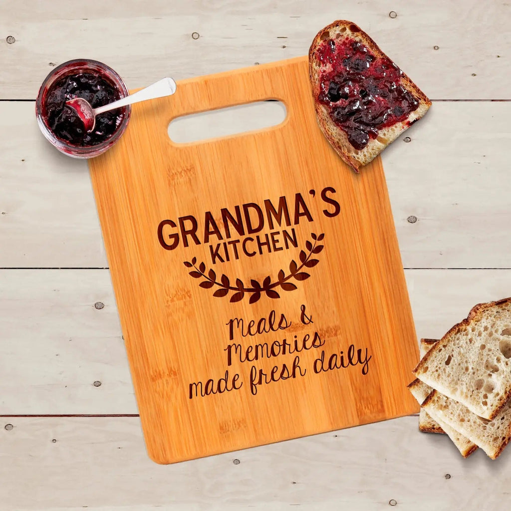 Square wood cutting board with handle cutout and engraved “GRANDMA’S KITCHEN”