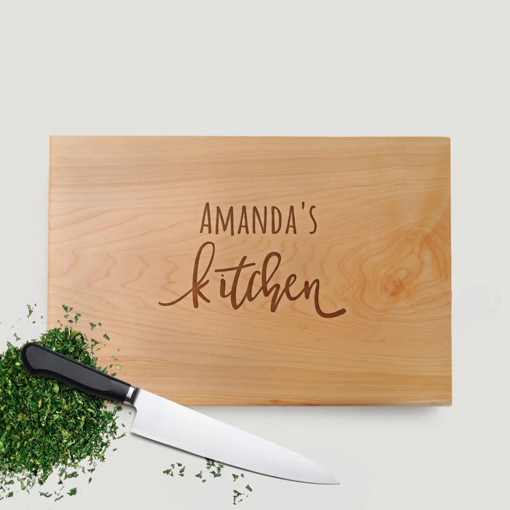 Personalized wood cutting board with engraved “Amanda's Kitchen” and chef's knife