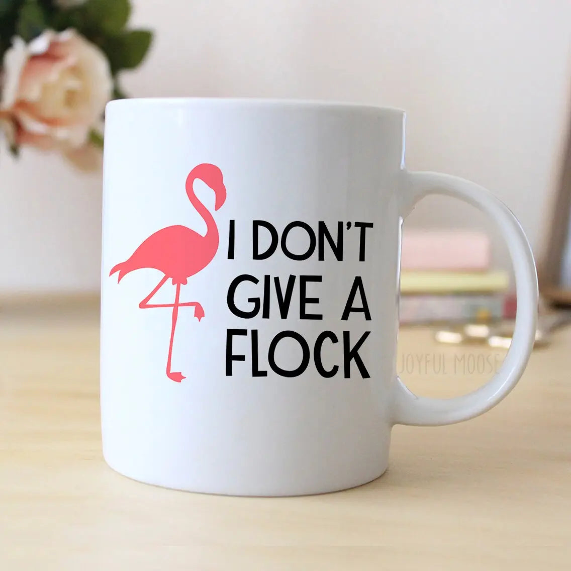 White ceramic coffee mug with pink flamingo and 'I DON'T GIVE A FLOCK' design