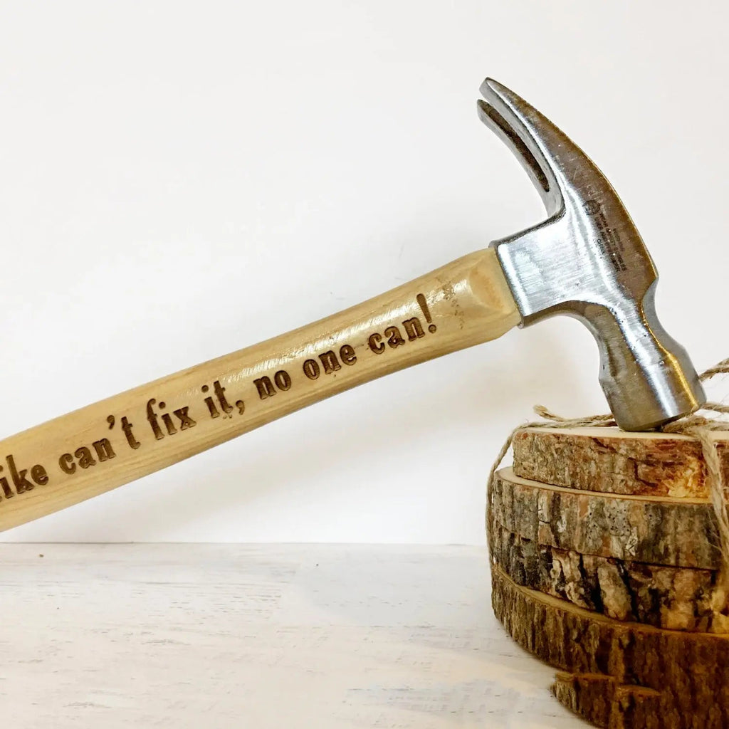 Personalized claw hammer with engraved handle resting on a wooden stump