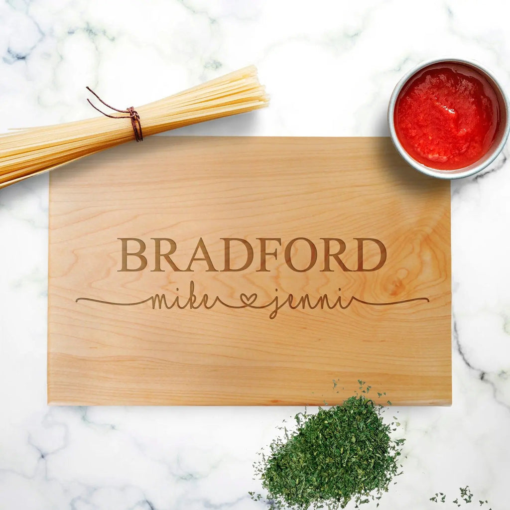 Personalized wood cutting board in light wood with engraved names and hearts