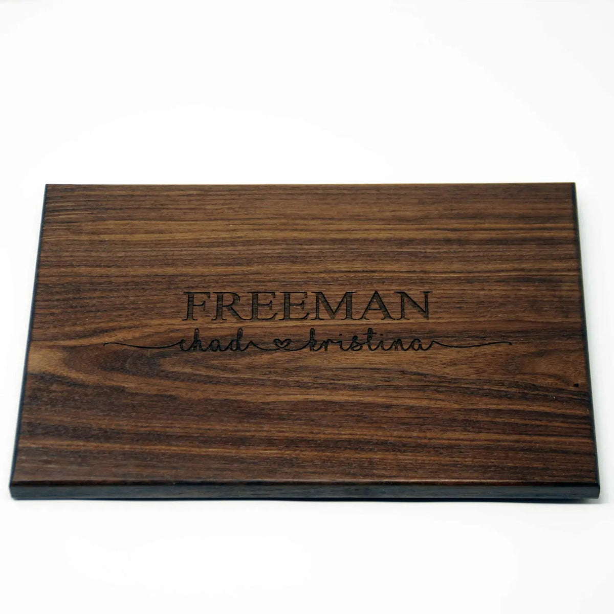 Personalized dark wood cutting board with engraved FREEMAN name and script