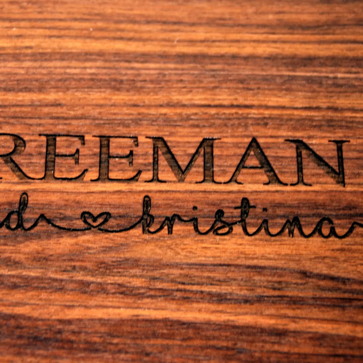 Close-up of engraved name and heart on a wood cutting board surface