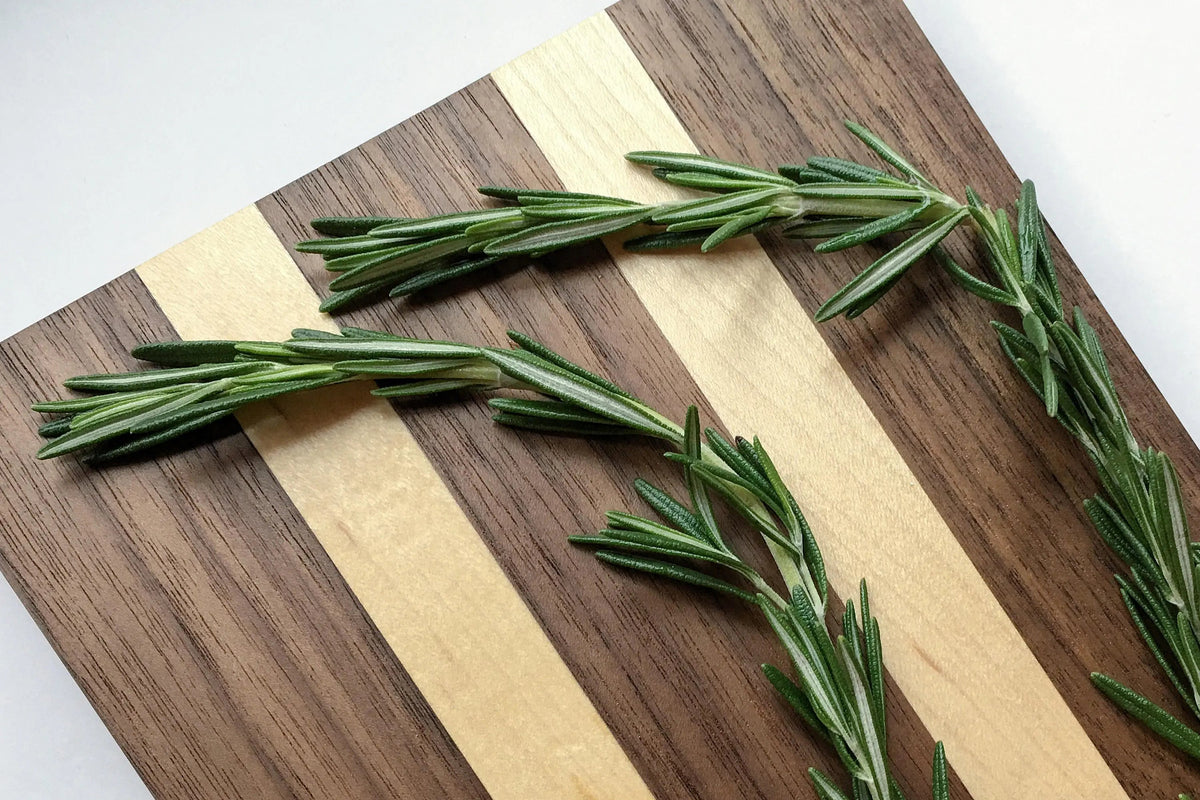 Striped maple and walnut wood serving board with rosemary sprigs
