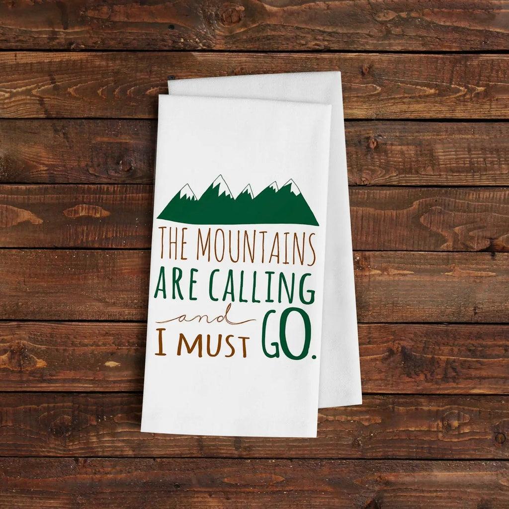 White kitchen towel with green mountain graphic and 'THE MOUNTAINS ARE CALLING' text