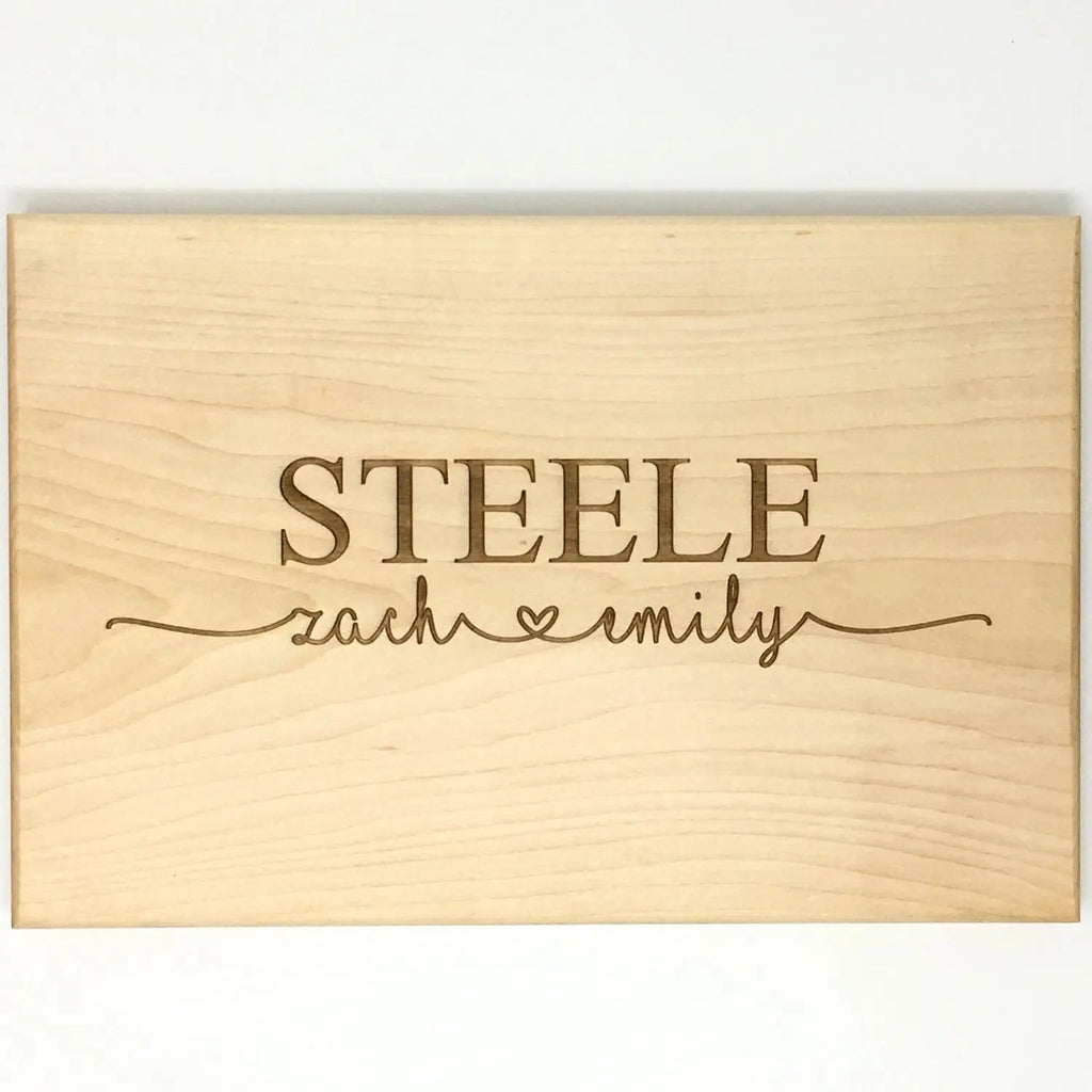 Personalized light wood cutting board with engraved STEELE name and script text