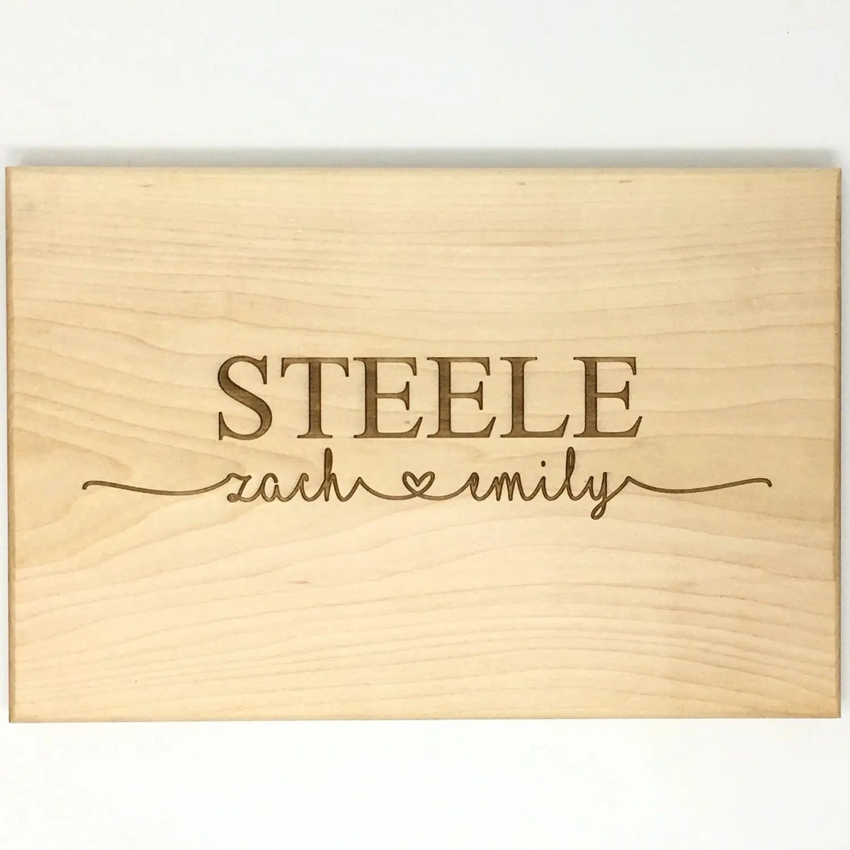 Personalized light wood cutting board with engraved STEELE name and script text