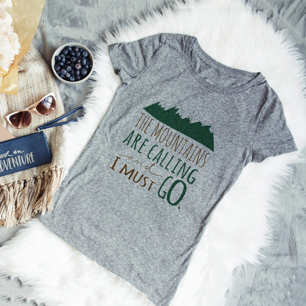 Gray crewneck unisex t-shirt with mountain graphic and "I must go" on the front