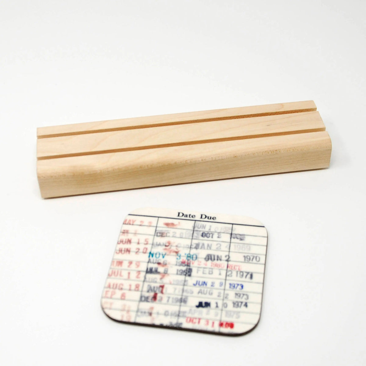 Library due-date coaster with Date Due grid, plus light wood display base.