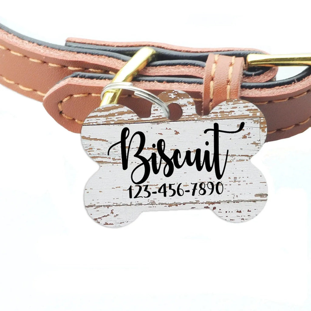 Weathered wood-pattern pet ID tag on brown leather collar, engraved Bisquit and phone number