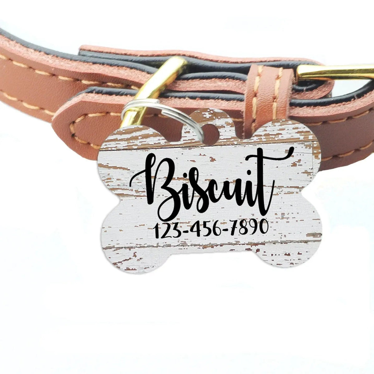 Weathered wood-pattern pet ID tag on brown leather collar, engraved Bisquit and phone number
