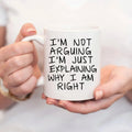 White ceramic coffee mug with humorous quote in black lettering, held in a hand