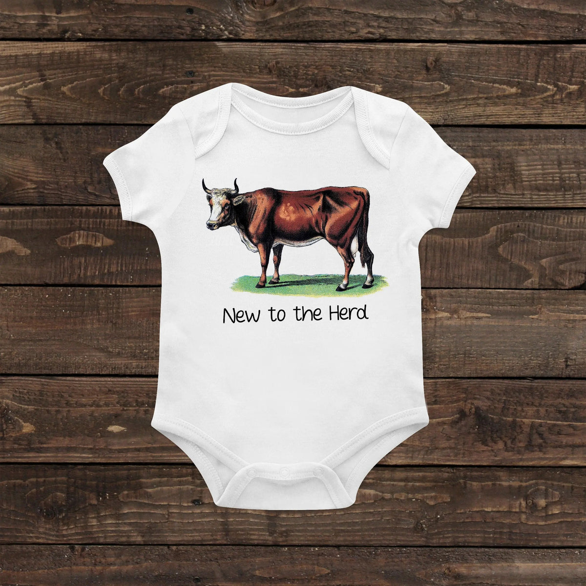 White newborn short-sleeve baby bodysuit with cow graphic and “New to the Herd” text