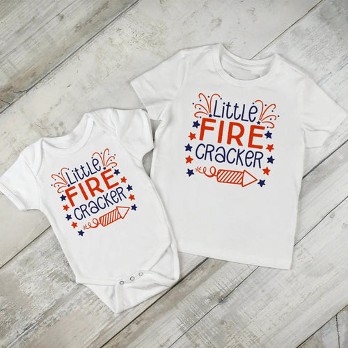 White baby bodysuit with “Little Fire Cracker” graphic in red, blue, and stars