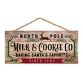 Rustic hanging wooden sign with green 'North Pole Milk & Cookie Co' lettering