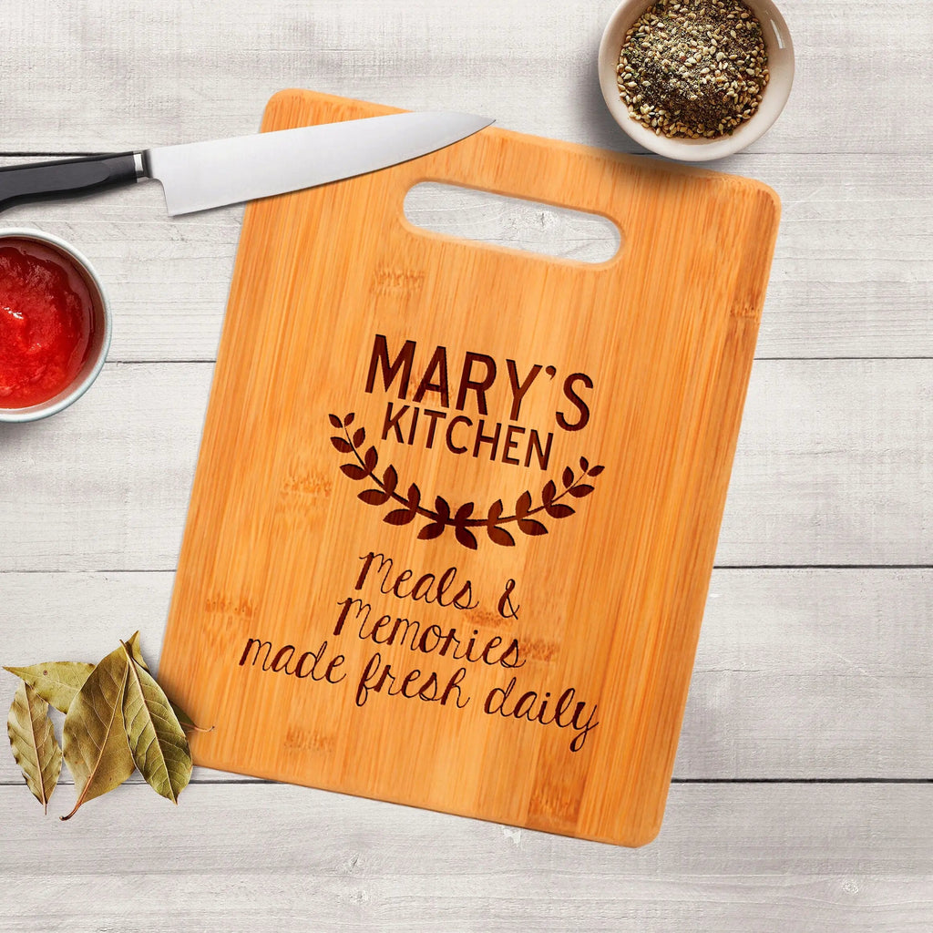 Wood cutting board with handle cutout and engraved “MARY’S KITCHEN”