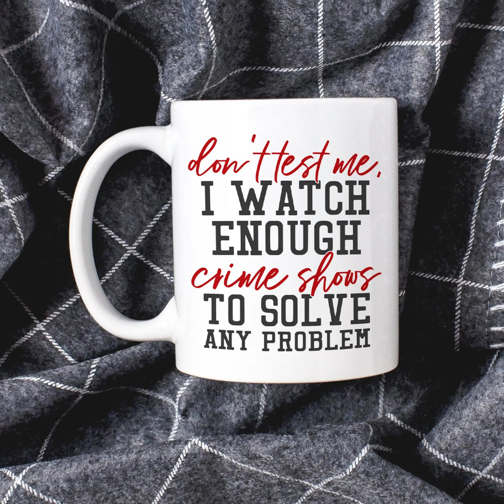 White coffee mug with 'don't test me, I watch enough crime shows to solve' text