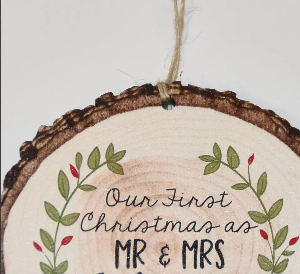Rustic wood slice Christmas ornament close-up with Our First Christmas MR & MRS wording