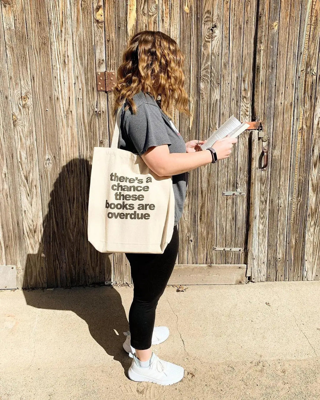 Canvas tote bag on shoulder with printed quote: there's a chance these books are overdue
