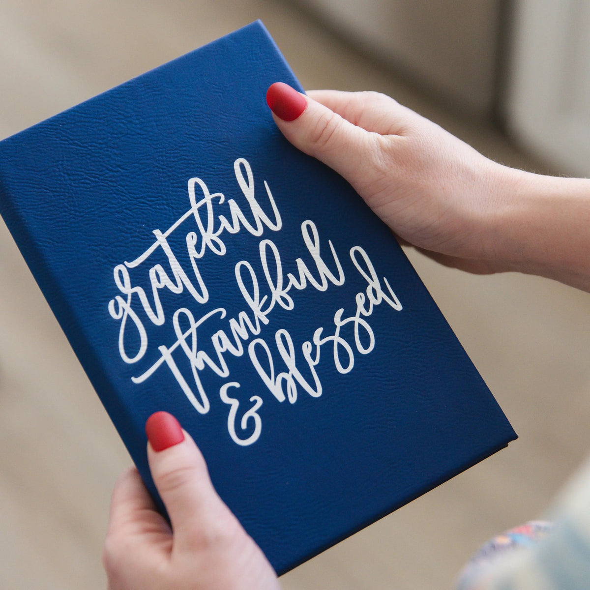 Blue gratitude writing journal with white script “grateful thankful blessed” on cover