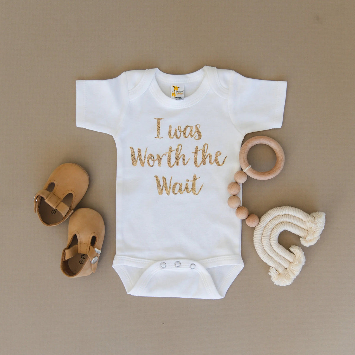 White newborn short-sleeve onesie with gold 'I was Worth the Wait' script