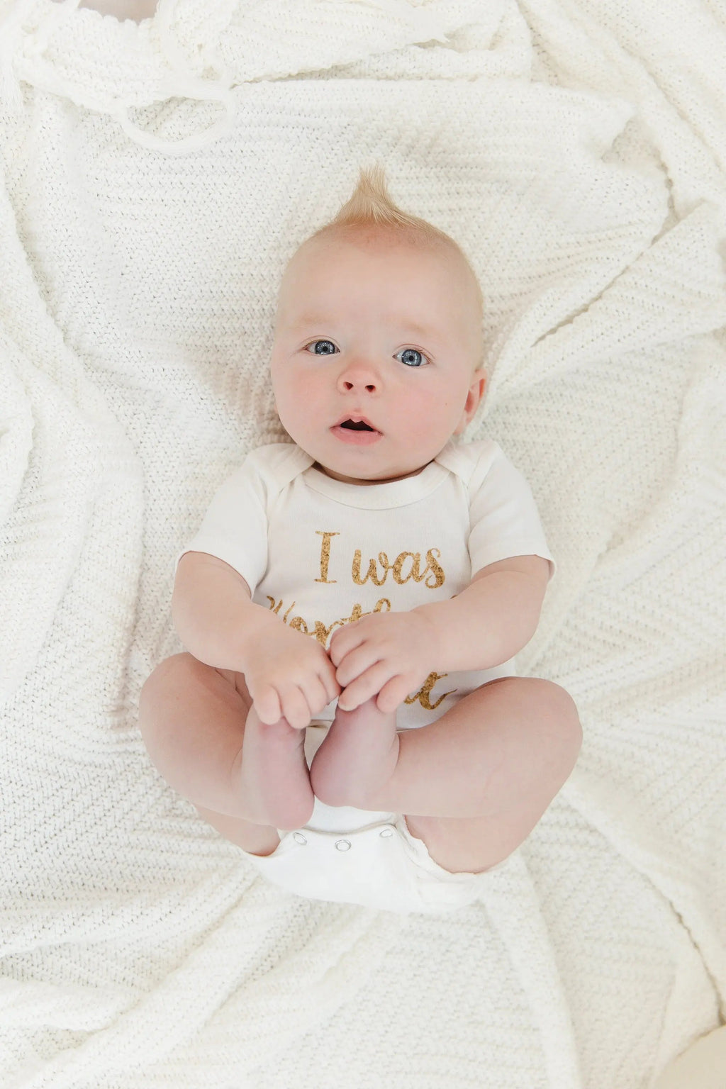 White newborn onesie with gold 'I was Worth the Wait' slogan on baby