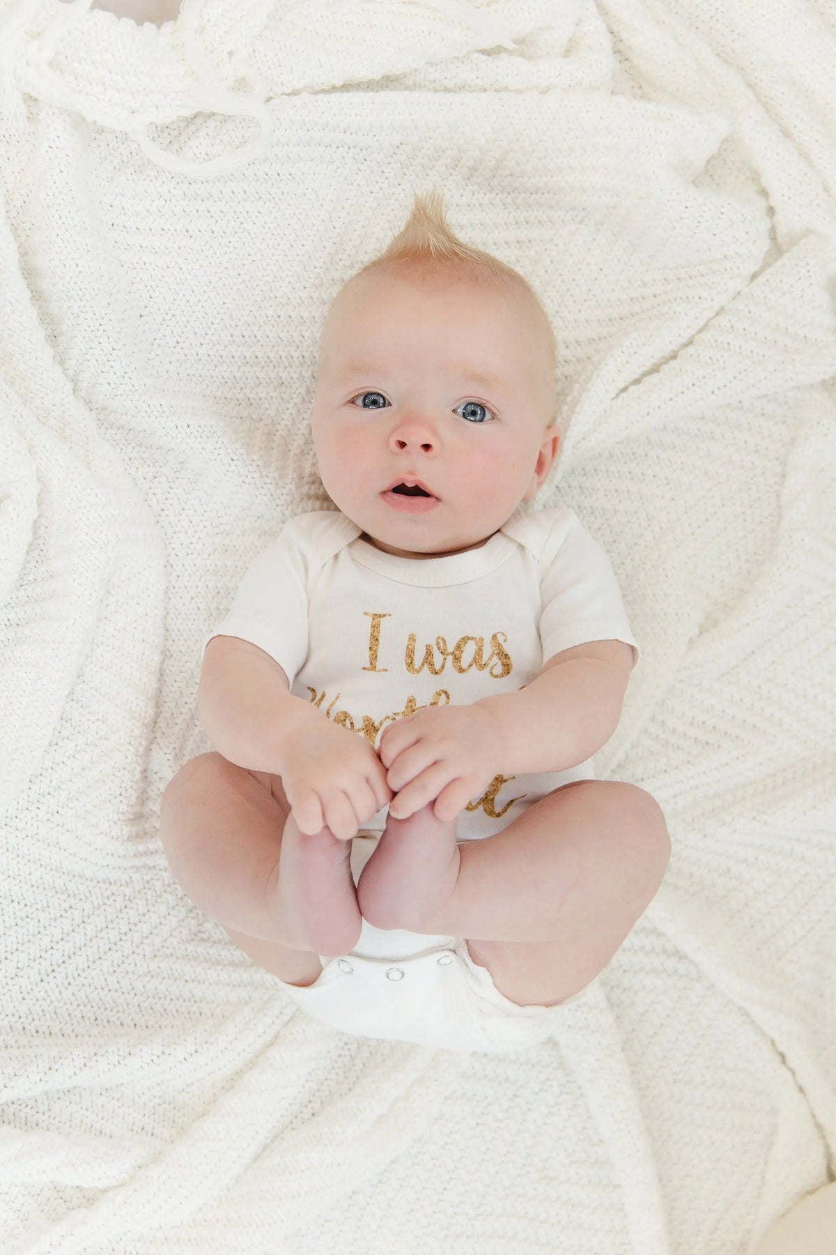 White newborn onesie with gold 'I was Worth the Wait' slogan on baby