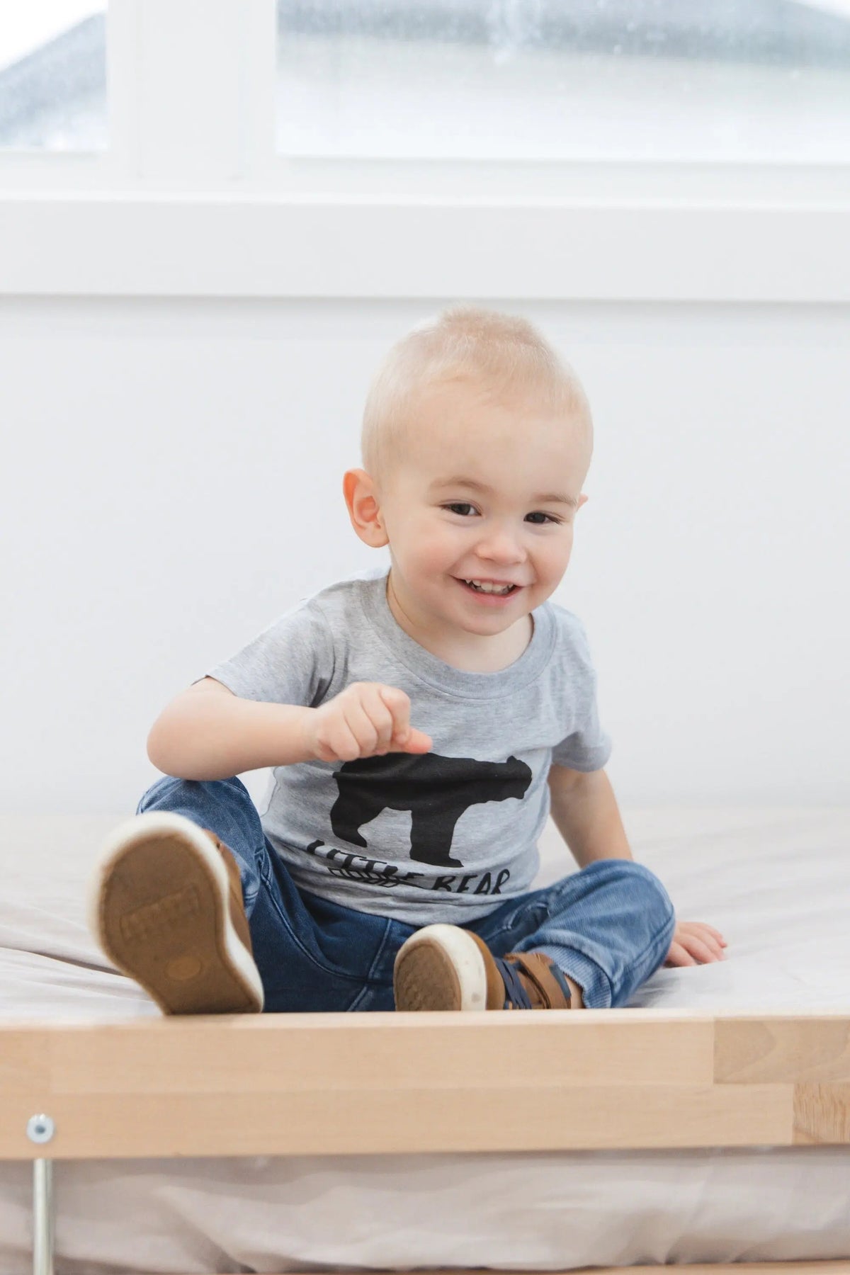 Child wearing gray T-shirt with black little bear and arrow graphic, short sleeves