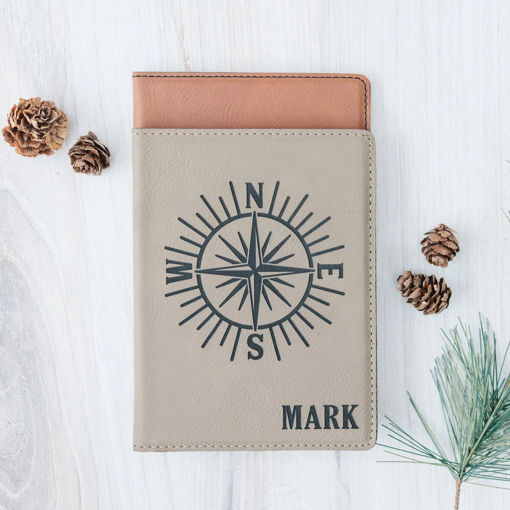 Light faux leather passport holder with compass emblem and 'MARK' engraving.