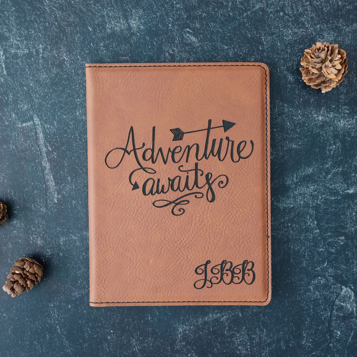 Tan personalized passport holder with “Adventure awaits” engraving and bottom initials
